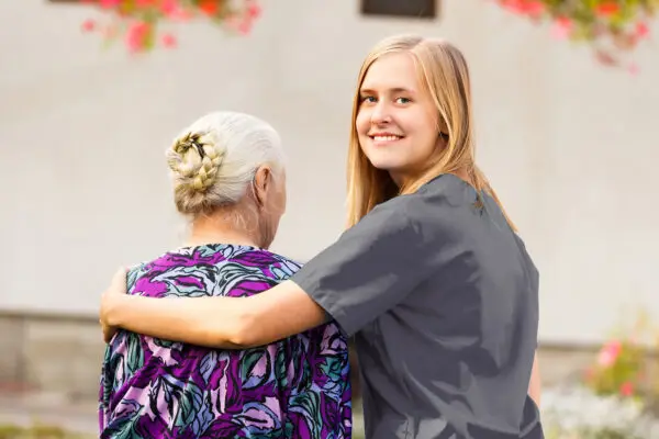 Care worker with her arms over an elderly patient's shoulder